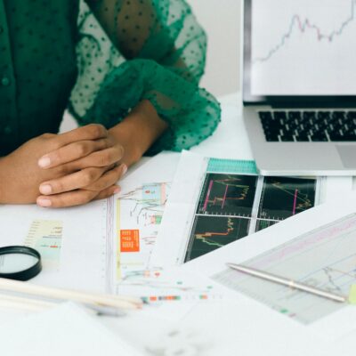 A person analyzes financial charts and graphs at a desk, indicating business trading activity.